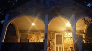A stone building with a porch featuring three arches and a door with a sign above it.