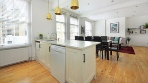 A modern kitchen with a central island, white cabinetry, and pendant lighting. - 110 m² luxury two-bed apartment in Earls Court (London)