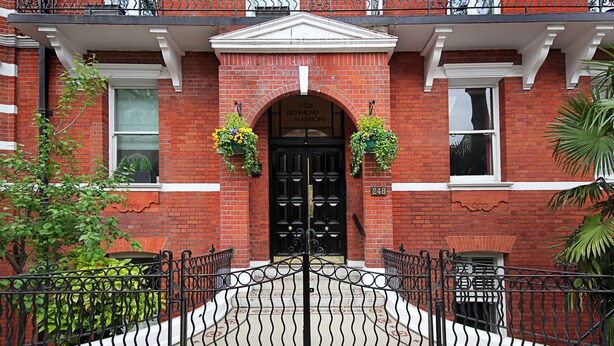 A red brick building with a black double door, a white entrance canopy, and a number "248" on the wall. - 110 m² luxury two-bed apartment in Earls Court (London)