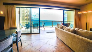 A spacious living area with a large sliding glass door leading to a balcony with a view of the ocean.