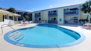 Una piscina amb un indicador de profunditat de 3 peus, envoltada per un edifici amb balcons i un cel serè.