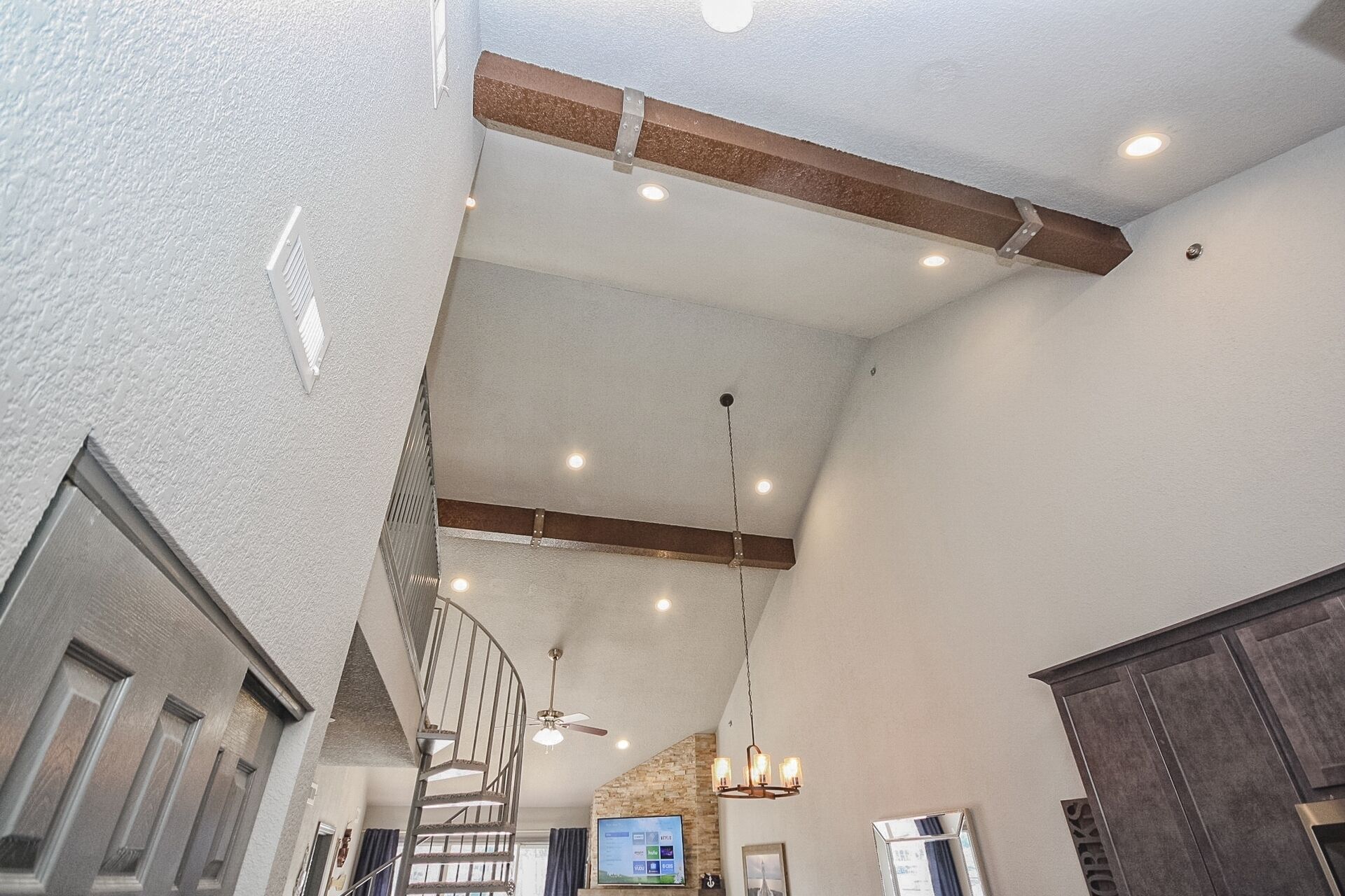 Un intérieur spacieux avec un plafond haut, des poutres apparentes et un escalier en colimaçon.