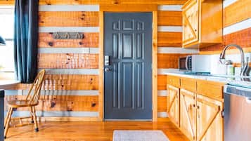 Un intérieur en bois avec une porte noire, des placards en bois, un four à micro-ondes et une chaise.
