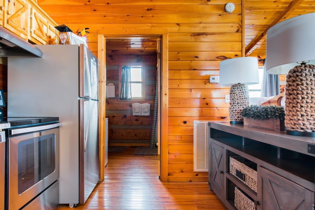 Un intérieur en bois avec un espace cuisine comprenant un réfrigérateur, un four et des placards.
