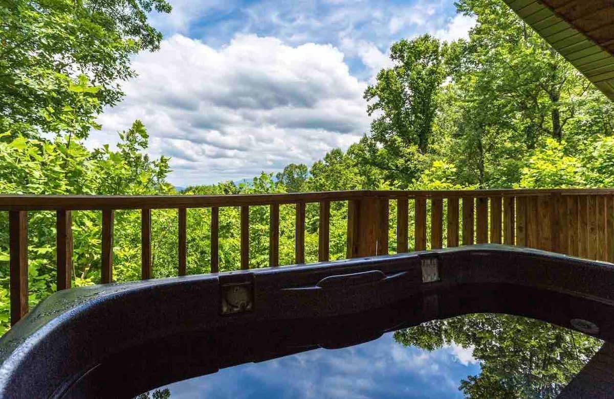 Ein Whirlpool mit einer Holzterrasse und Blick auf ein bewaldetes Gebiet.