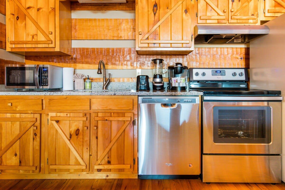 Une cuisine dotée de meubles en bois et d’appareils électroménagers en acier inoxydable, notamment un lave-vaisselle, un four à micro-ondes, une machine à café et une cuisinière.