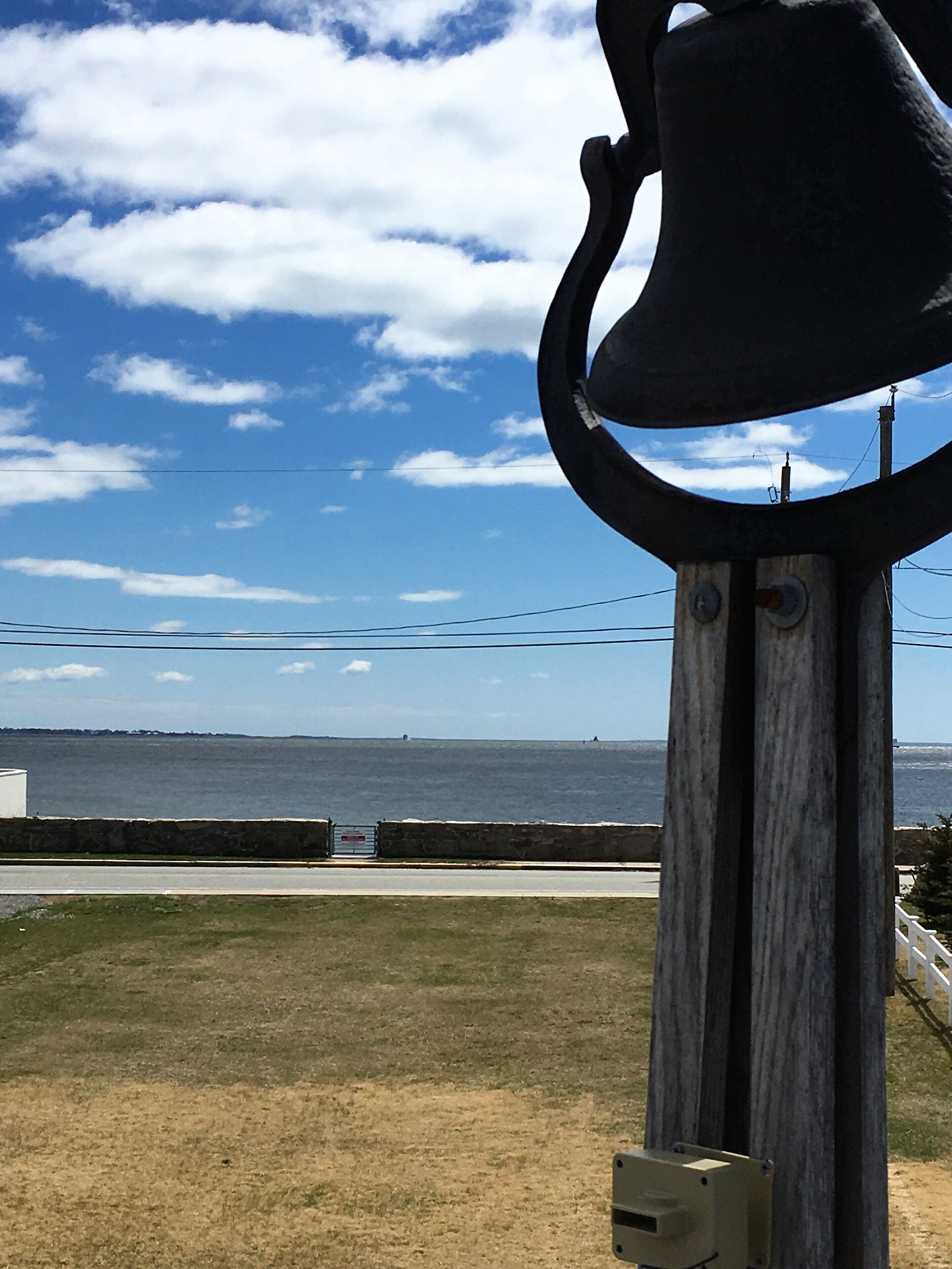 A large bell structure with a view of the ocean and a clear sky.