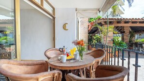 A round table with chairs, a glass of orange juice, a mug, and a vase with flowers. - Beachfront Condo on Los Muertos Beach, Puerto Vallarta / Romantic Zone / Amapas (Puerto Vallarta)
