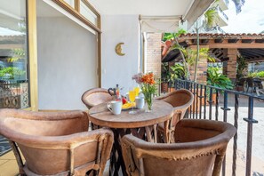 Ein runder Tisch mit Stühlen, ein Glas Orangensaft, eine Tasse und eine Vase mit Blumen.