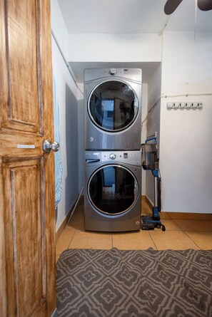 Un lavadero con dos lavadoras apiladas, una puerta de madera y una alfombra estampada.