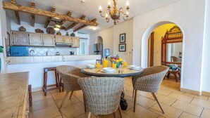 Un coin repas avec une table ronde, des chaises en osier et un lustre.