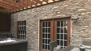 A stone building with a hot tub, a covered patio, and outdoor seating.