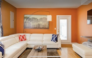 A living room with a white sectional sofa, a coffee table, and a painting on the wall.