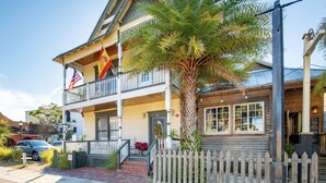 A two-story building with a balcony, a palm tree, and a picket fence. - 1880 Victorian In Heart Of Downtown  (St. Augustine)