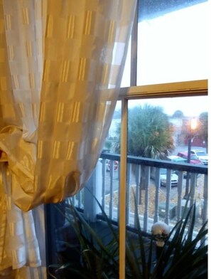 Enjoy the view from your balcony overlooking the surrounding area with potted plants and a glimpse of the city beyond.