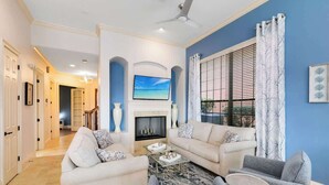 A living room with a fireplace, sofas, a coffee table, and a television. - Spacious, game room, golf view, private pool & BBQ (Kissimmee)