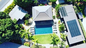 Eine Luftaufnahme eines Wohnhauses mit Schwimmbad, Solaranlage und üppiger Bepflanzung.