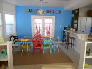 Enjoy meals in this vibrant dining area with a wooden table and colorful chairs.