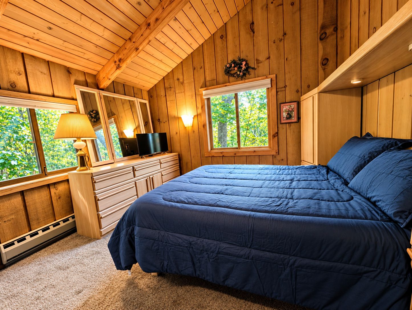 A bedroom with a bed, dresser, and two windows.