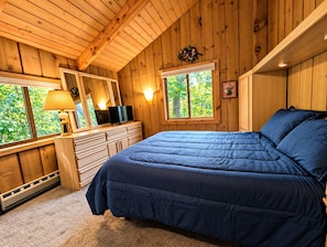 Un dormitorio con cama, cómoda y dos ventanas.