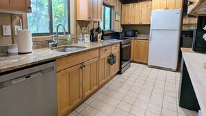 Eine Küche mit Holzschränken, einer Edelstahlspüle, einer Mikrowelle, einem Kühlschrank und einem Geschirrspüler.