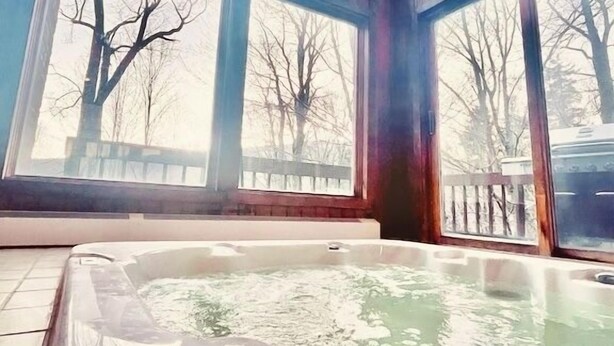 Ein Whirlpool mit Blick auf die durch Fenster gut einsehbaren, kahl stehenden Bäume.