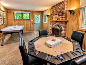 Una habitación con mesa de billar, mesa de póker y chimenea.