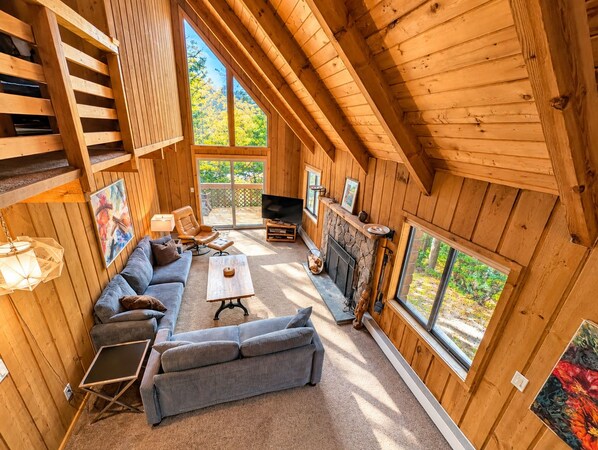 A cozy wooden cabin interior with a sofa, a coffee table, and a fireplace.