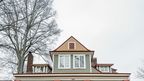 Une maison à deux étages avec un porche à l’avant, un escalier et une façade en briques.