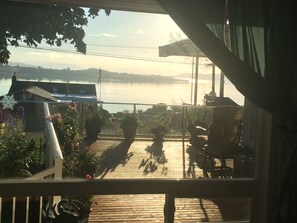A wooden deck with potted plants and a view of a lake. - Private home w FANTASTIC Views. Huge yard. All 10 star reviews. Pet friendly! (Oak Harbor)