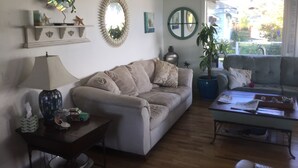 Een zithoek met een bank, salontafel, lamp, bijzettafeltje en een potplant.