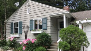 A house with a front porch, a satellite dish, and a stone wall with a small garden. - Guest Cottage on Country Estate (Watertown)