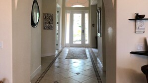 A hallway with an arched ceiling, patterned floor tiles, and a door at the end. - Waterfront Pool Home with Gulf Access (Cape Coral)