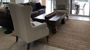 A spacious living room with a chandelier, a sofa, a chair, and a coffee table. - Waterfront Pool Home with Gulf Access (Cape Coral)