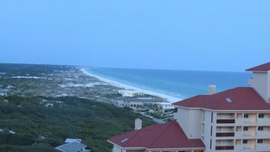 A coastal view with a beach, buildings, and greenery.