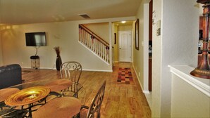A dining area with a wooden table and chairs, a TV mounted on the wall, and a staircase leading to another room. - Air & Space Force Basic Training Grads/Ex-Large home mins from Lackland AFB/Golf (San Antonio)
