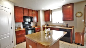 A kitchen with wooden cabinets, a granite countertop, a microwave, an oven, a dishwasher, and a clock on the wall. - Air & Space Force Basic Training Grads/Ex-Large home mins from Lackland AFB/Golf (San Antonio)