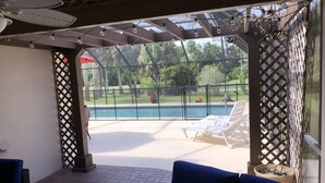 A covered patio area with a pool, lounge chairs, and a blue sofa.
