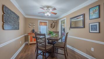 A dining area with a wooden table, four chairs, a ceiling fan, and a wall-mounted map.