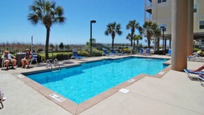 A swimming pool with lounge chairs and palm trees. - Beach Lover's Condo With Spectacular Ocean View, Pool, Lazy River, & Jacuzzi!  (North Myrtle Beach)