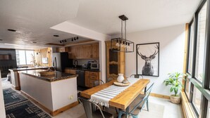 A modern kitchen with wooden cabinets, a central island, and a dining area with a wooden table and chairs.