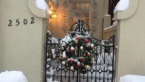 A snow-covered gate with a Christmas wreath, a number '2502' on the wall, and a lit wall lamp. - Stunning Mediterranean Monument Avenue flat in the heart of RVA's Fan District (Richmond)