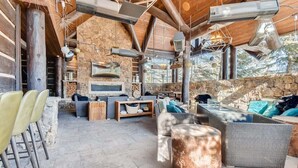 A rustic outdoor seating area with stone walls, a stone fireplace, and a variety of seating options including sofas and chairs. - Luxury Ritz Carlton 2BR Residence - Ski-in/out & Private Laundry (Beaver Creek)