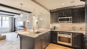 A modern kitchen with dark cabinetry, stainless steel appliances, and pendant lighting. - Luxury Ritz Carlton 2BR Residence - Ski-in/out & Private Laundry (Beaver Creek)