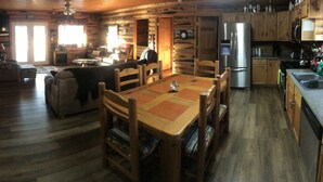 Interior de una cabaña de madera con comedor, cocina y sala de estar.