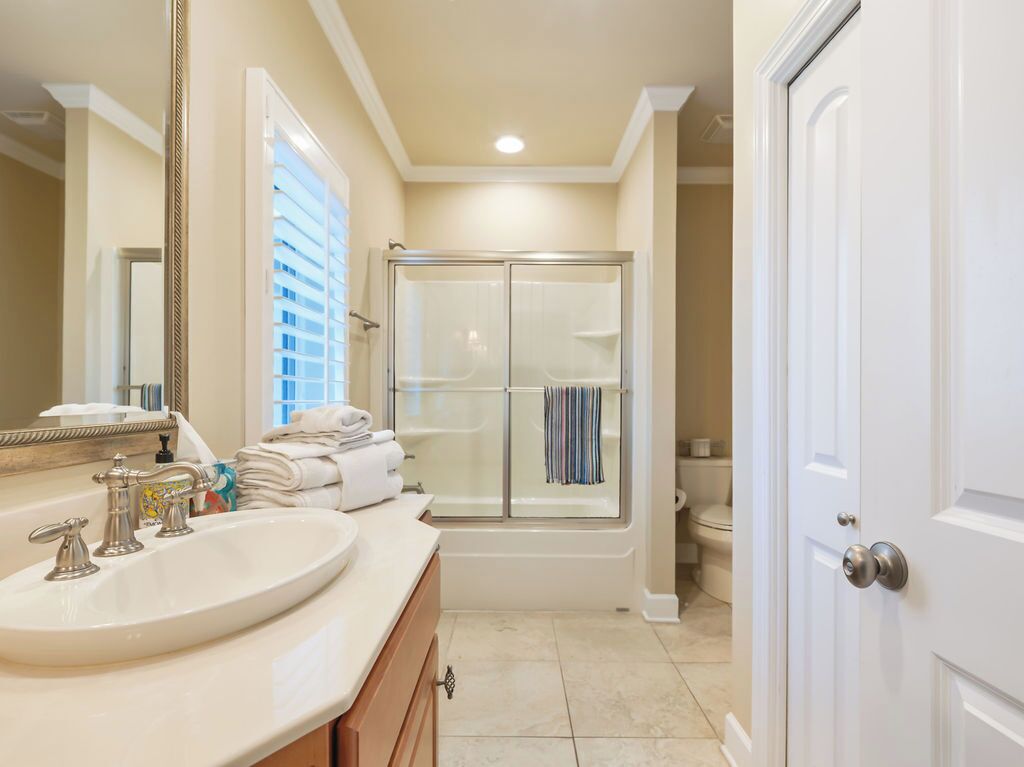 A bathroom with a sink, mirror, shower, and toilet.
