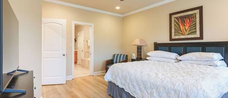 A bedroom with a bed, a ceiling fan, a nightstand, a lamp, and a door leading to another room.