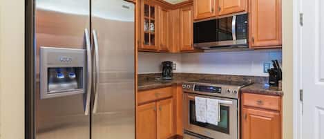 Une cuisine équipée d’appareils électroménagers en acier inoxydable, de meubles en bois et d’un sol carrelé.