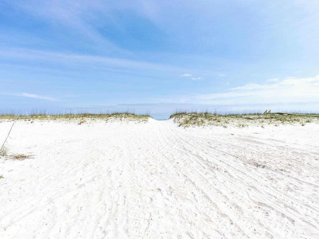 A sandy beach with dunes and a clear sky.