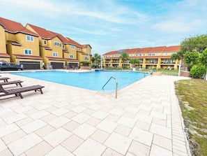 En swimmingpool med liggestole og en patio i mursten.